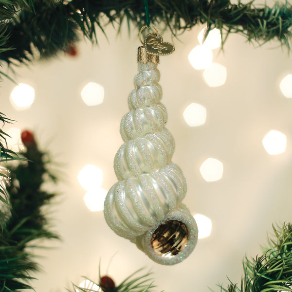 White wentletrap shell ornament hanging on a lit Christmas tree with soft bokeh lights