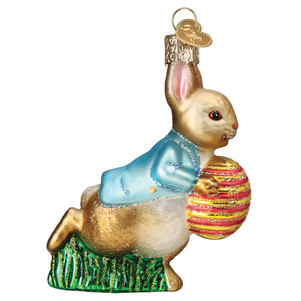 Right side of the Peter Rabbit ornament leaping over green grass with a pink and gold striped egg
