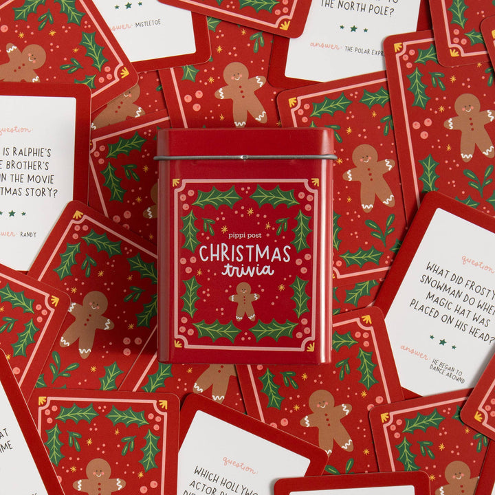 Christmas trivia storage tin on a spread of question cards about holiday movies and traditions