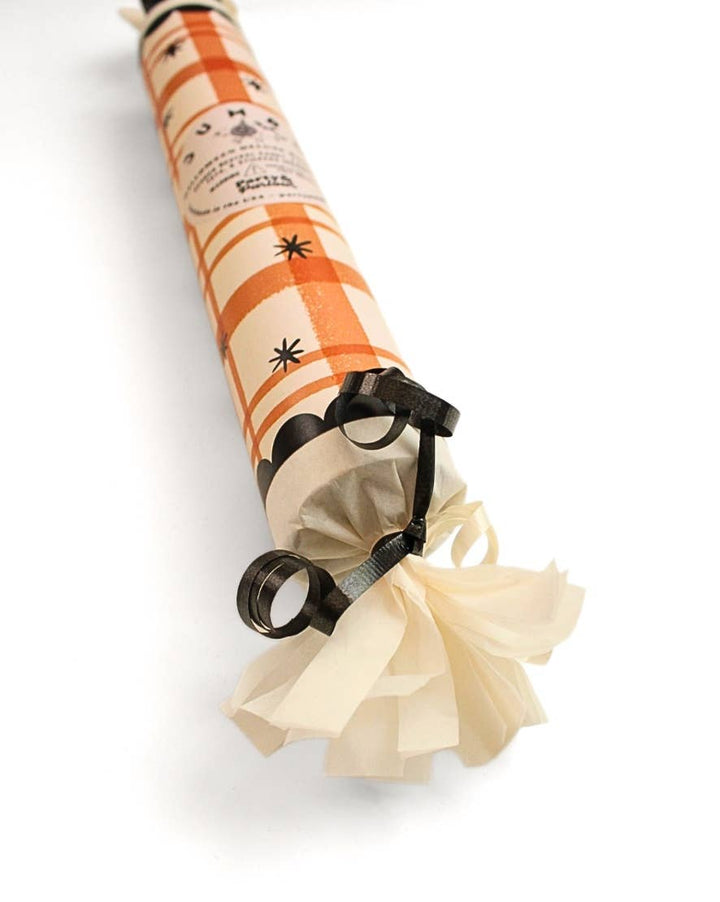 Angled view of the orange plaid Halloween bon bon showing black fringe and ribbon ties for a Halloween place setting