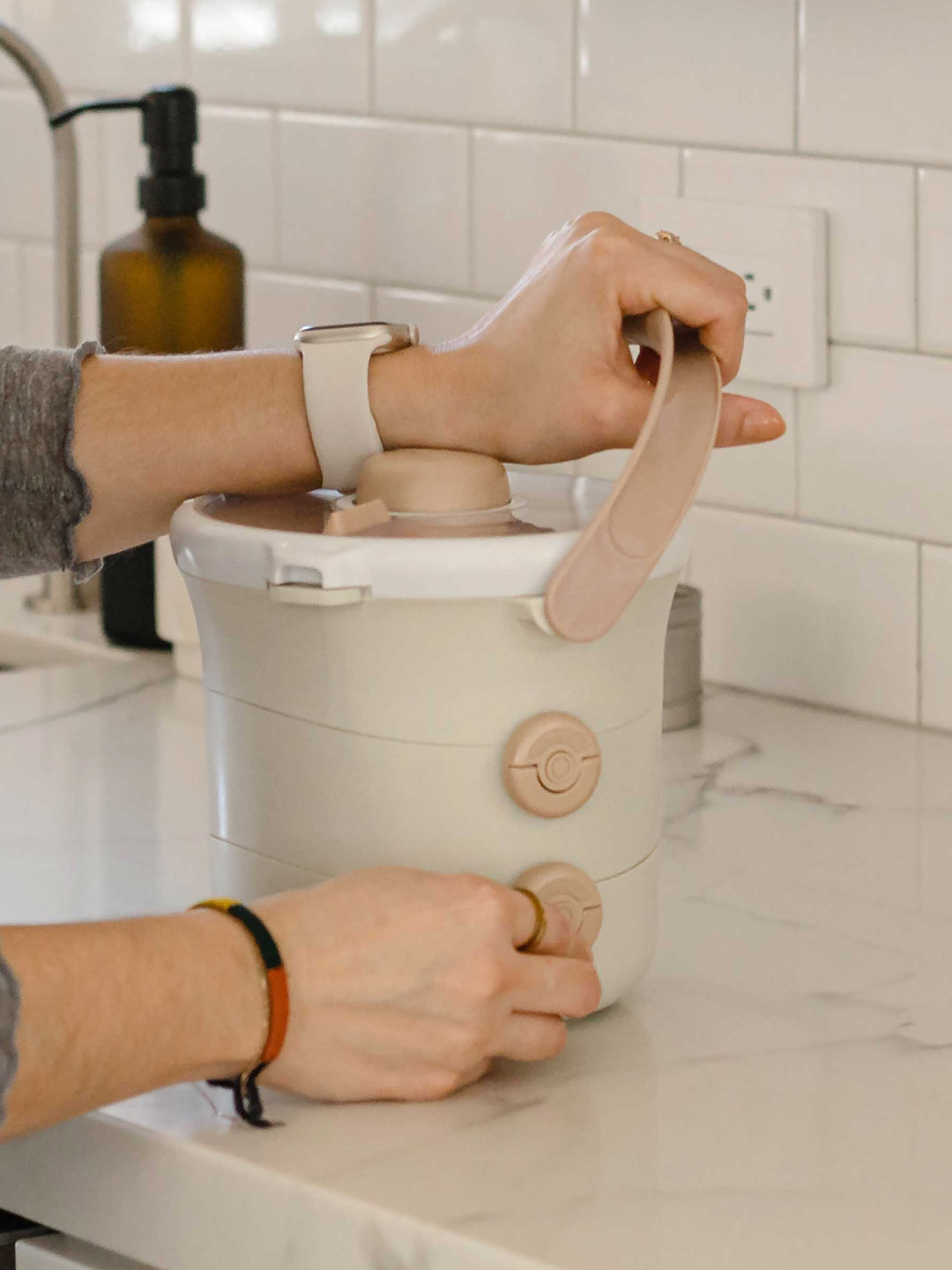 Adult rinsing the cream Lunch Stack at a kitchen sink