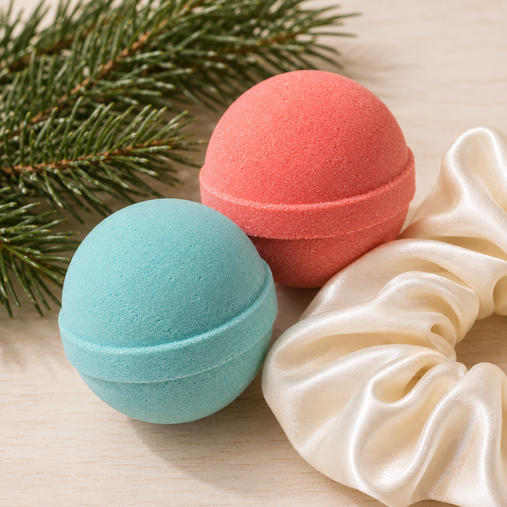 Close-up of aqua and coral mini bath bombs with a satin scrunchie and fir branch, a festive spa pairing