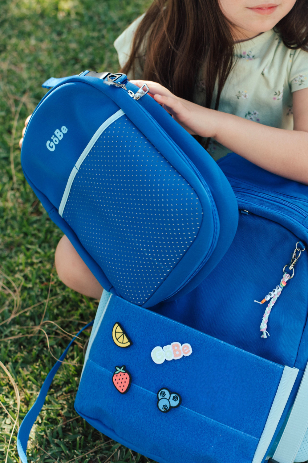 Close-up of the blue GoBe lunch bag clipped to a blue backpack