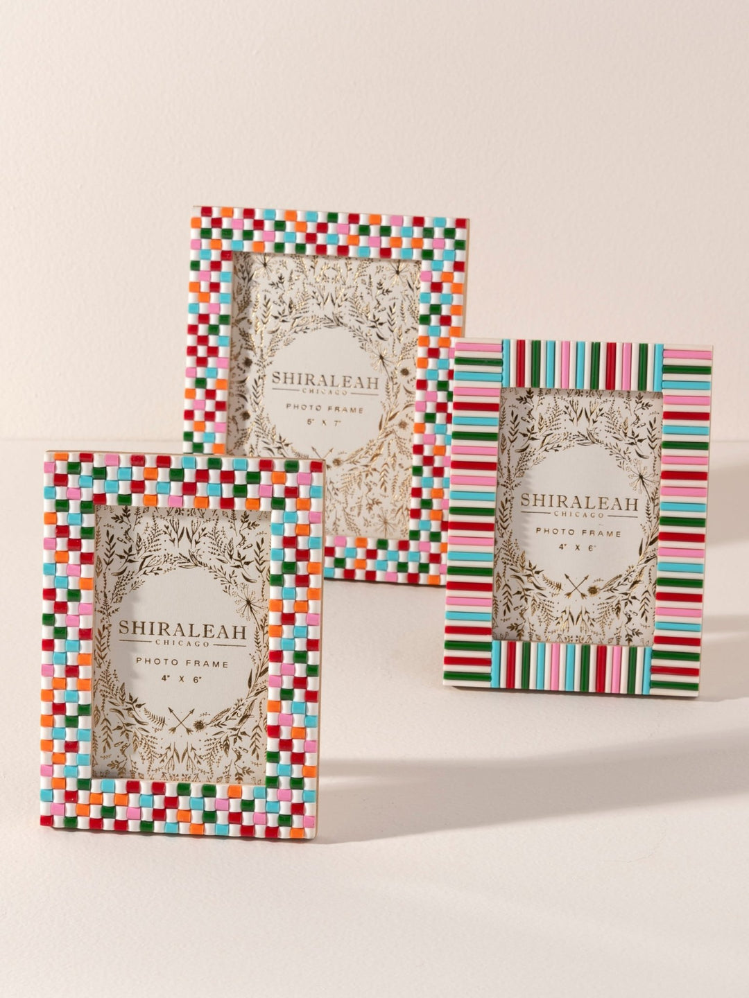 Three Shiraleah decorative photo frames with colorful striped and checkered borders, displayed on a light beige background.