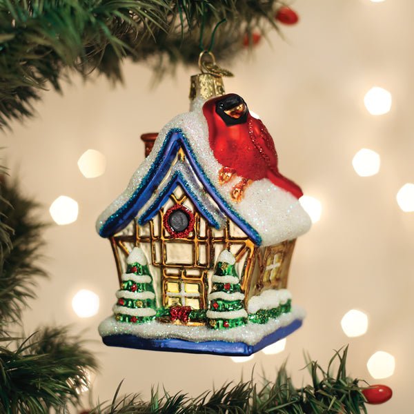 Cardinal birdhouse glass ornament with glowing windows hanging on a lit Christmas tree