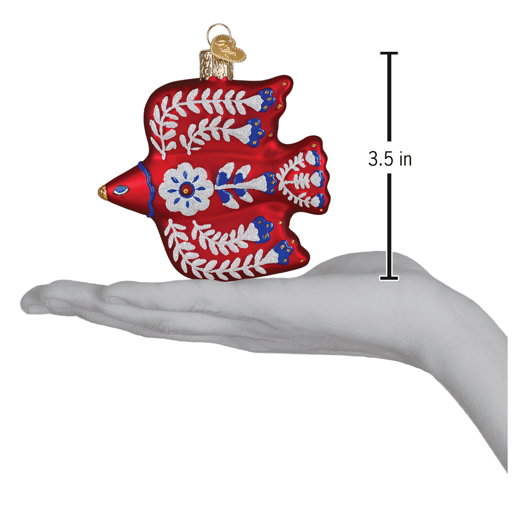 Folk art thrush ornament on an open palm beside a 3.5 inch height marker