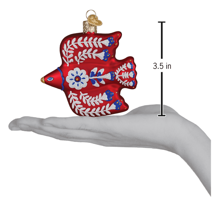 Folk art thrush ornament on an open palm beside a 3.5 inch height marker