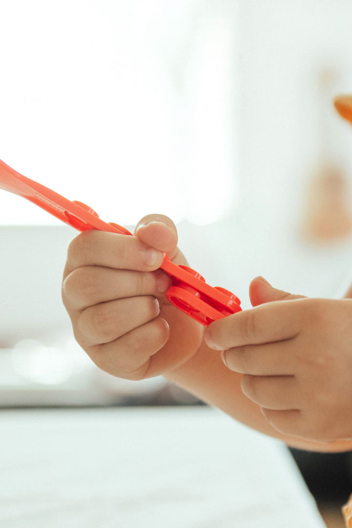 Child's hands snapping a red fork and spoon handle together