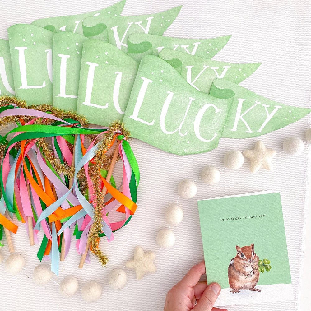 Green Lucky pennant flags styled with rainbow ribbons, a felt star garland, and a lucky-themed greeting card