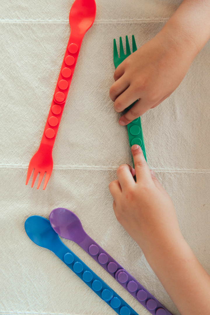 Overhead view of red, green, purple, and blue utensils being clicked together