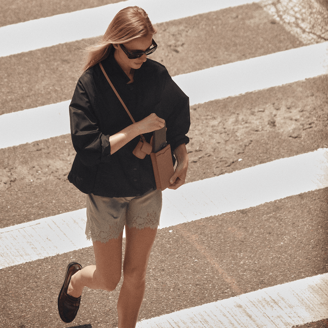 Woman in sunglasses crossing a street wearing the affogato Georgia phone sling crossbody