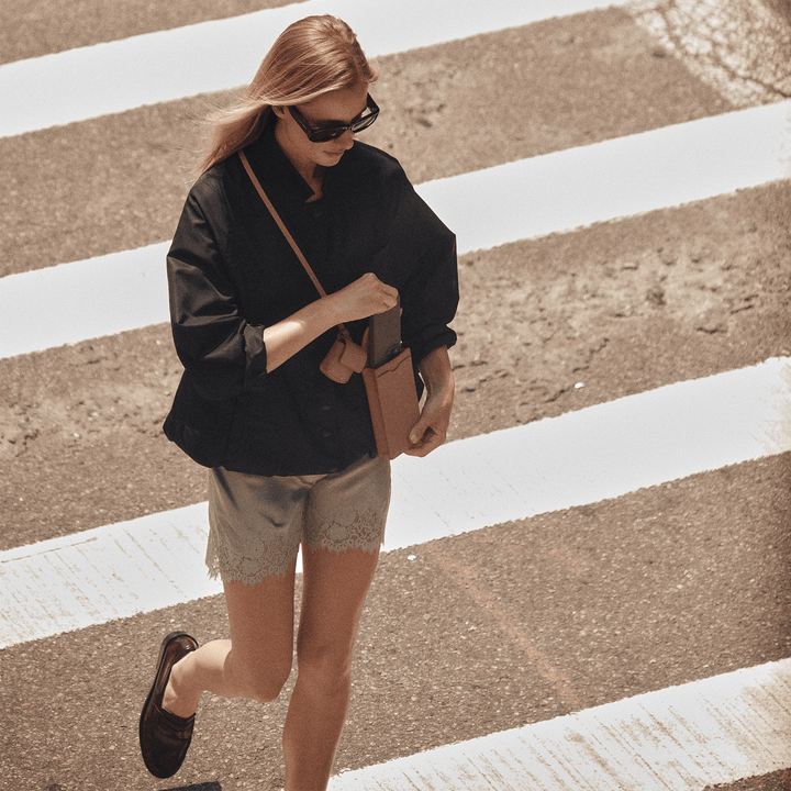 Woman in sunglasses crossing a street wearing the affogato Georgia phone sling crossbody