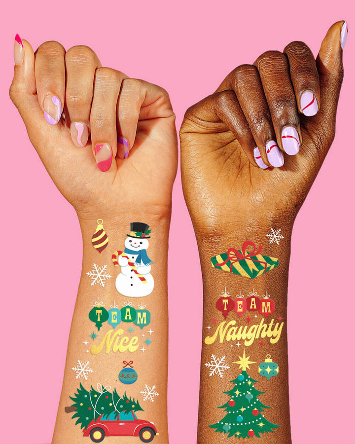 Two wrists wearing Christmas temporary tattoos including Team Nice, Team Naughty, a snowman, a Christmas tree, and a red car