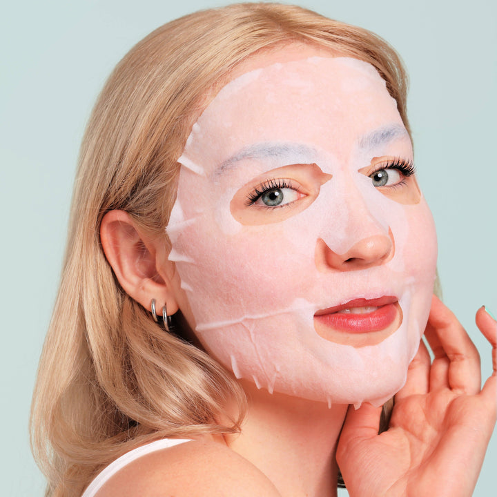 Model relaxing in the white egg yolk and shea butter sheet mask during a cozy holiday spa night