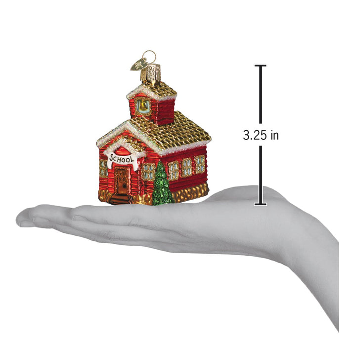Schoolhouse ornament resting on an open hand with a 3.25 inch scale marker beside it