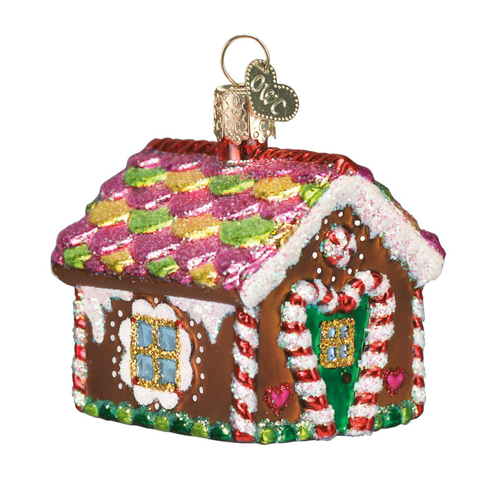 Gingerbread house ornament with a checkered candy roof and candy cane door frame, on white
