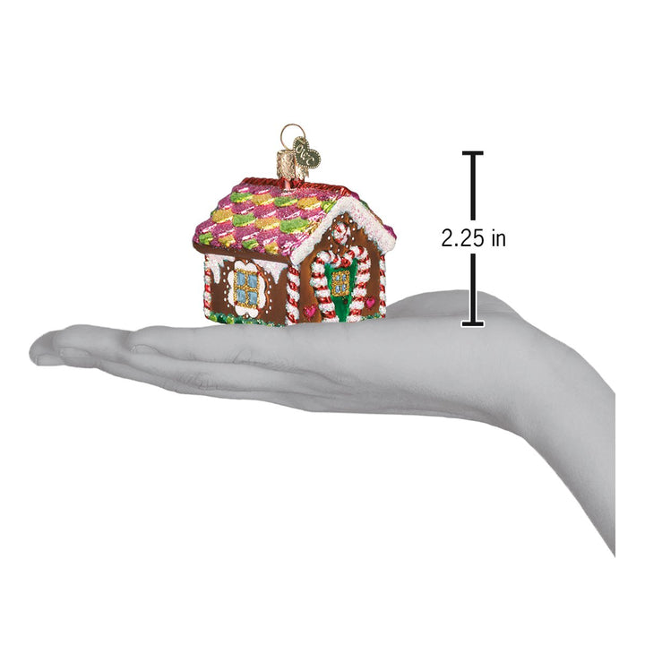 Gingerbread house ornament on an open palm beside a 2.25 inch height marker