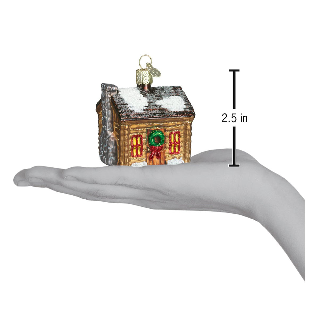 Log cabin ornament on an open palm with a 2.5 inch height marker