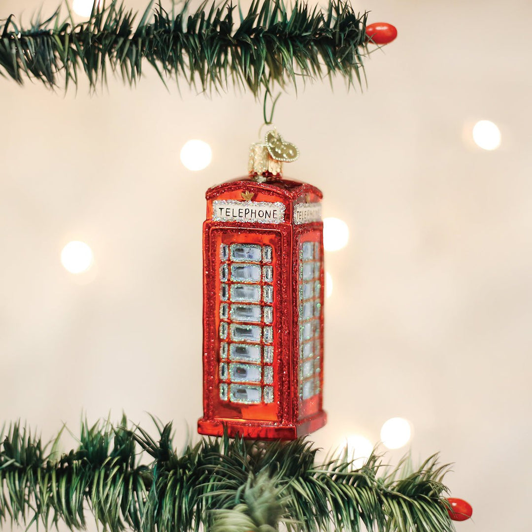 Red phone booth ornament hanging on a lit Christmas tree with warm bokeh lights