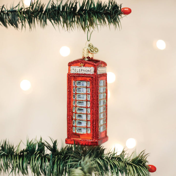 Red phone booth ornament hanging on a lit Christmas tree with warm bokeh lights