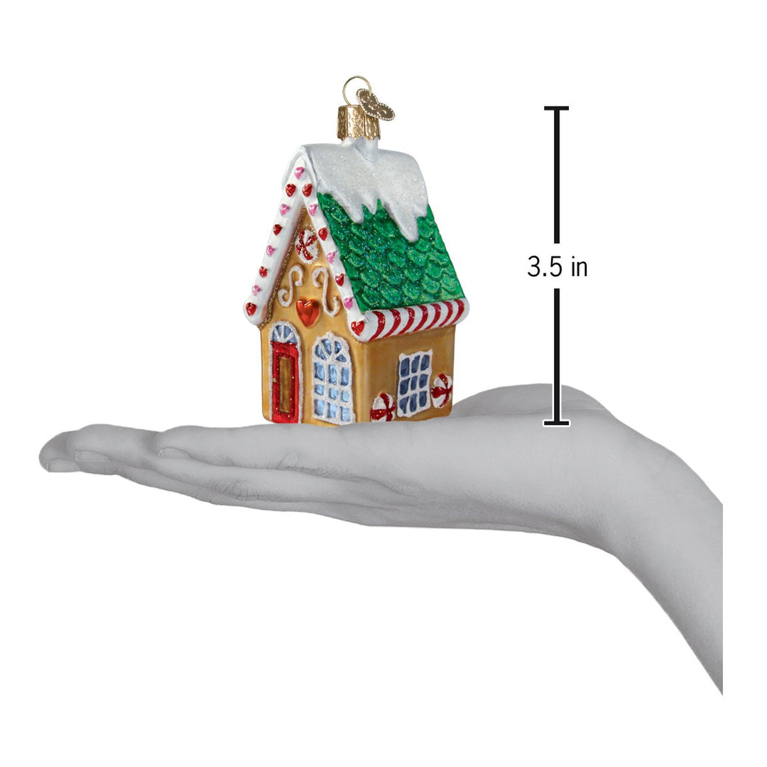 Gingerbread cookie cottage ornament on an open palm with a 3.5 inch height marker