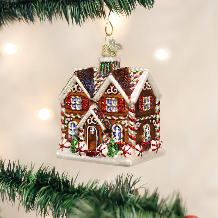 Christmastime cottage ornament hanging on a Christmas tree with warm bokeh lights