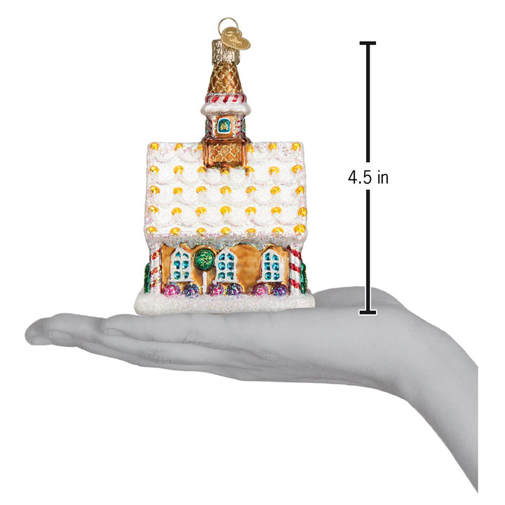 Gingerbread church ornament on an open palm beside a 4.5 inch height marker