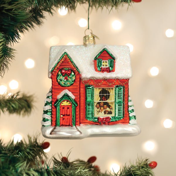 Red farmhouse ornament hanging on a lit Christmas tree with soft golden bokeh lights