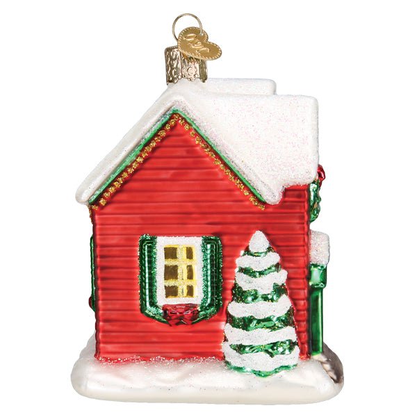 Side view of the red farmhouse ornament with a snowy evergreen and green shutters, on white