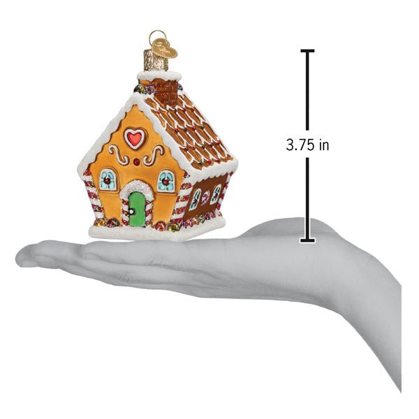 Gingerbread cottage ornament on an open palm beside a 3.75 inch height marker