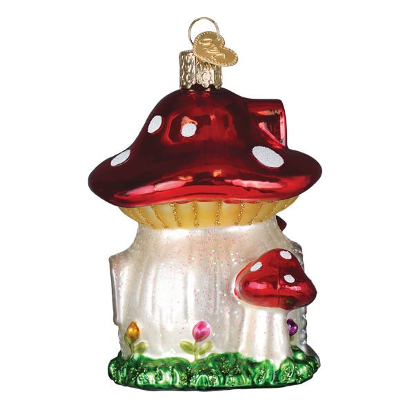 Side view of the mushroom house ornament showing a small toadstool and flowers at the base, on white