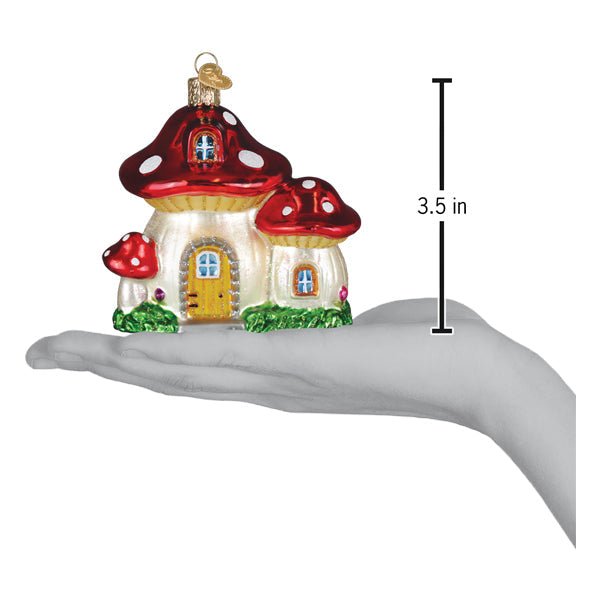 Mushroom house ornament on an open palm beside a 3.5 inch height marker