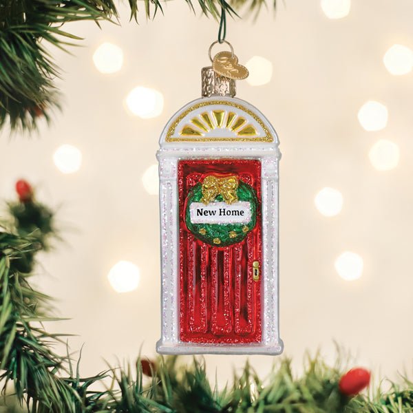 New Home front door ornament hanging on a Christmas tree with soft twinkle lights