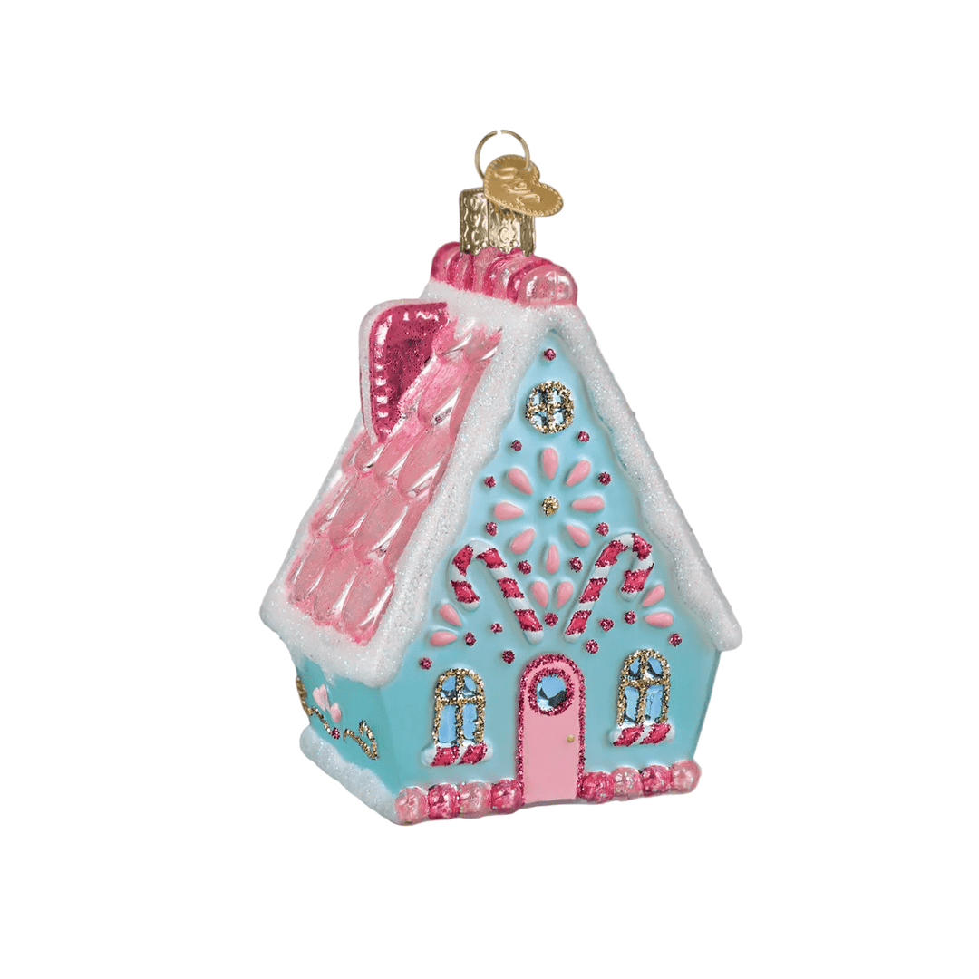 Decorative gingerbread house ornament on a Christmas tree with lights in the background