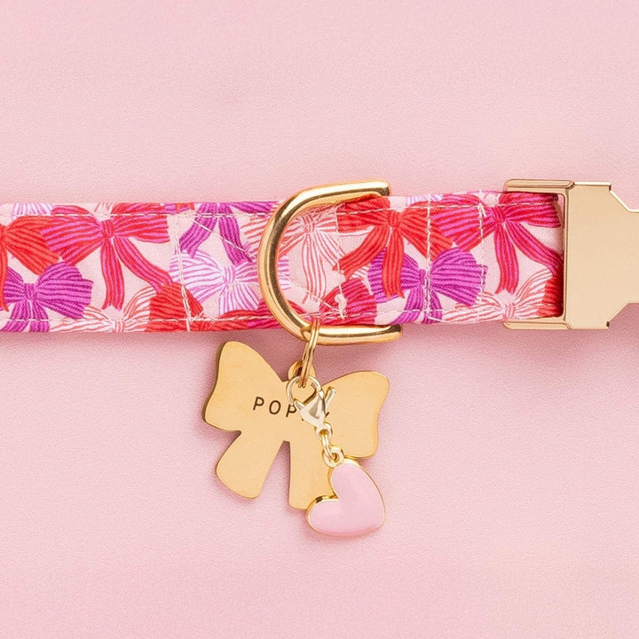 Pink and red bow print collar with a gold bow-shaped ID tag and the pink heart charm