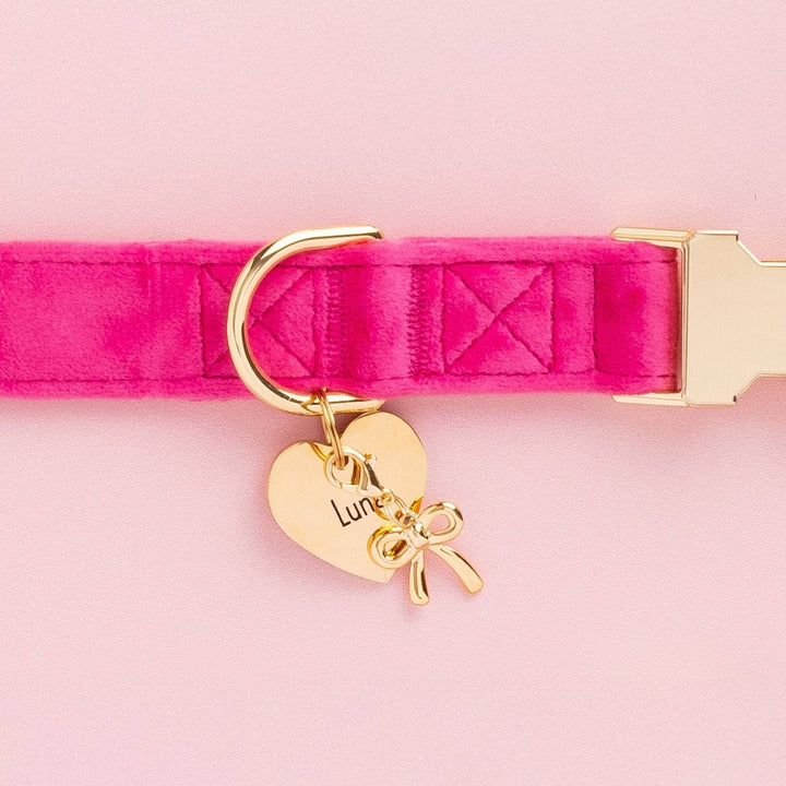 Hot pink velvet dog collar with a gold heart ID tag and bow charm on pink