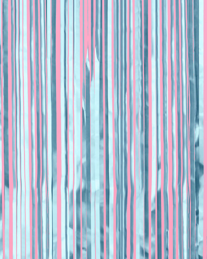 Light blue metallic fringe curtain strands hung against a pink wall as a bridal shower backdrop