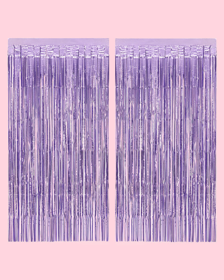 Two purple foil fringe curtain panels hung side by side on a pale pink wall