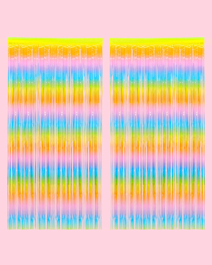 Two pastel rainbow fringe curtain panels hung side by side on a pale pink wall