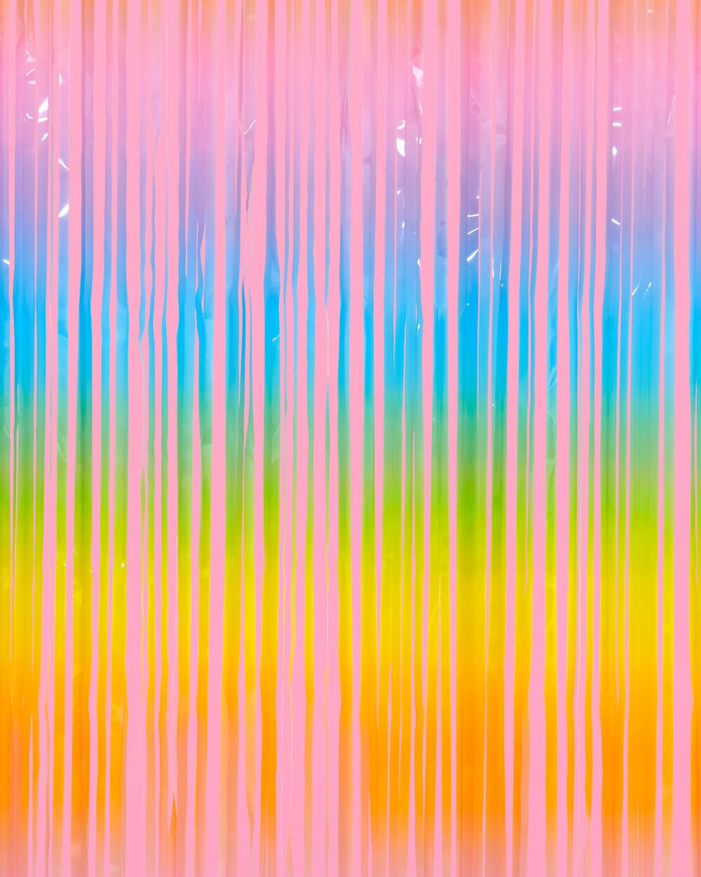 Pastel rainbow fringe curtain in pink, blue, yellow, orange, and green hung as a party backdrop