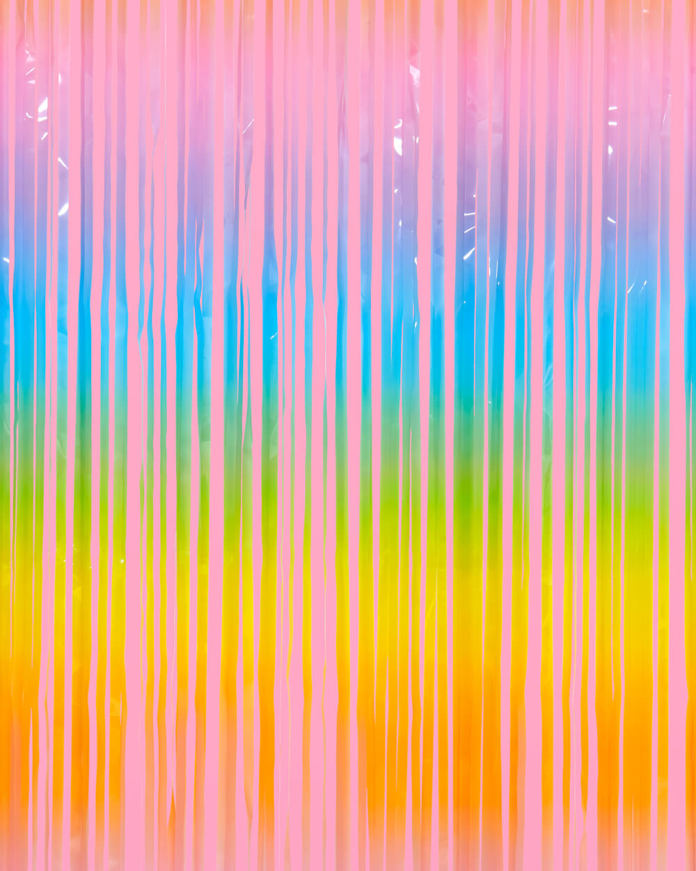 Pastel rainbow fringe curtain in pink, blue, yellow, orange, and green hung as a party backdrop