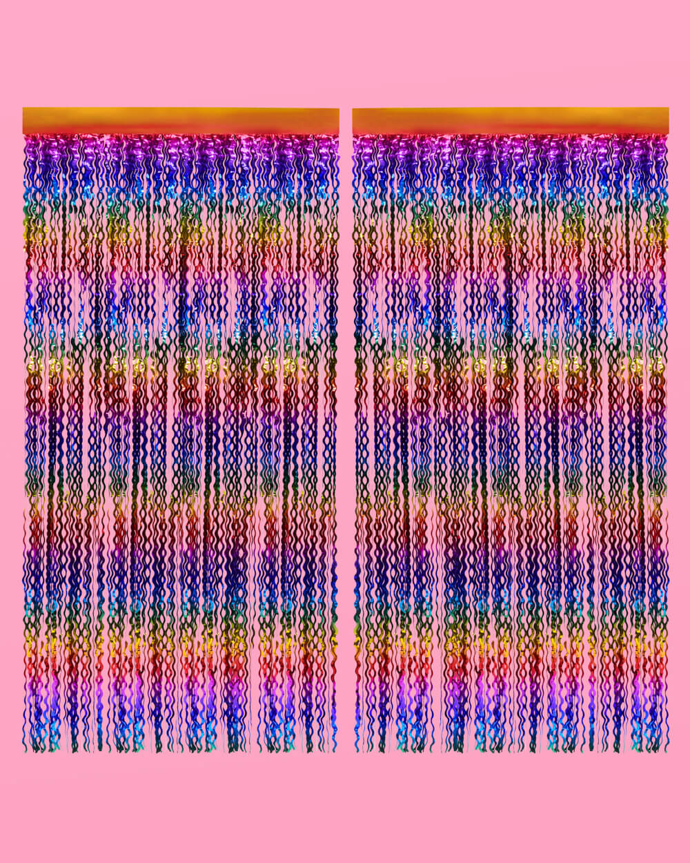 Two rainbow wavy foil curtain panels hung side by side on a pink wall