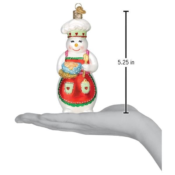 Snow woman chef ornament on an open palm beside a 5.25 inch height marker