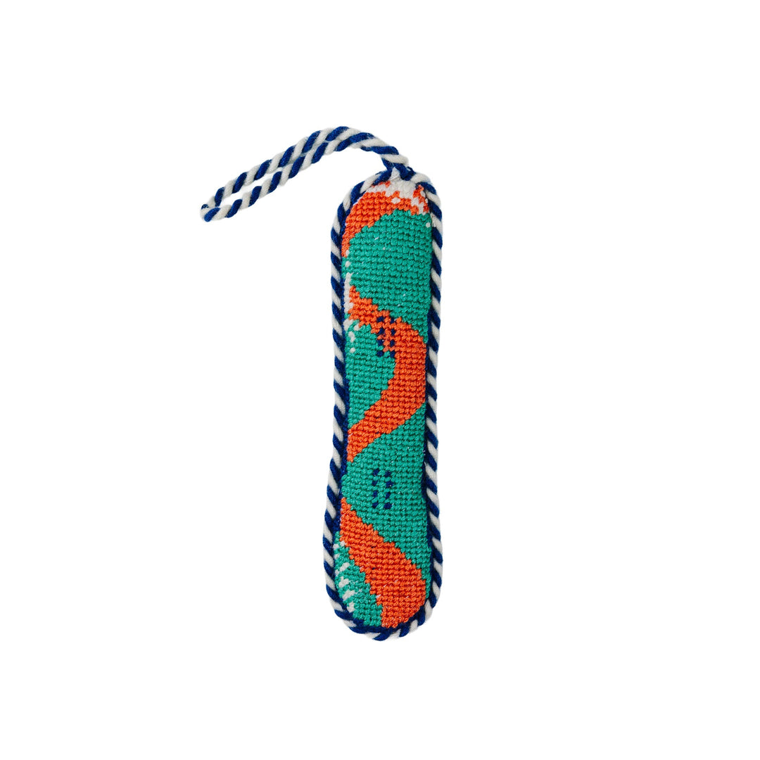 Snowboard needlepoint ornament in teal with an orange wave stripe and a navy and white twisted cord, front view