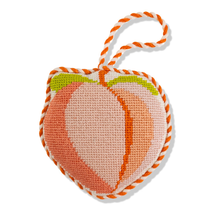 Peach needlepoint ornament, front view in orange and blush with a green leaf and orange and white cord