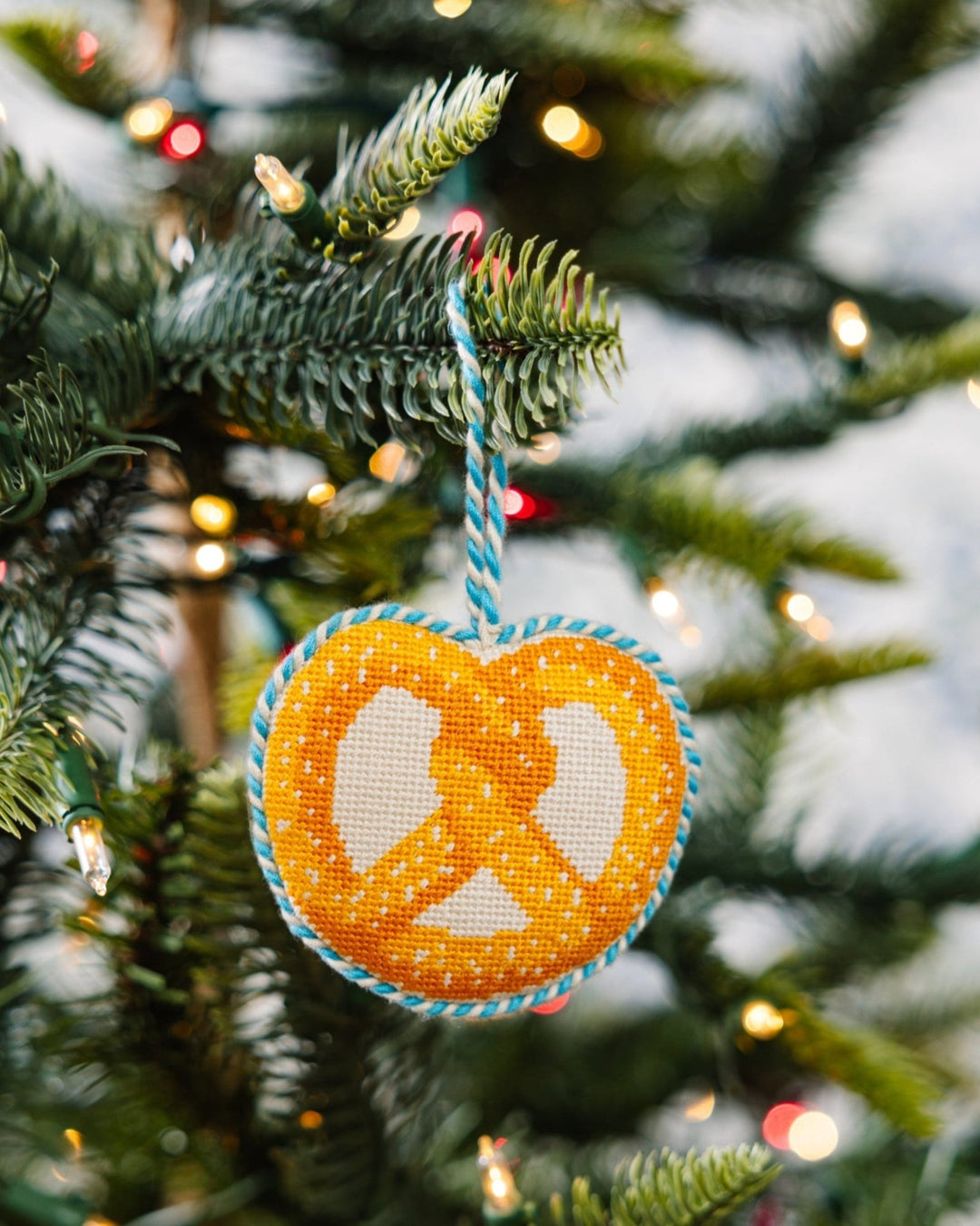 Pretzel ornament hanging on a Christmas tree branch among white lights