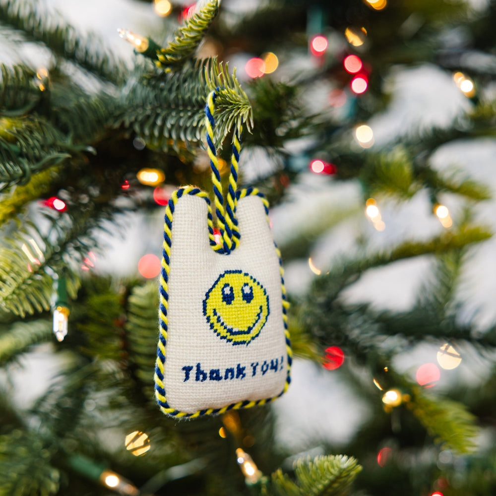 Thank You takeout bag ornament hanging from a Christmas tree branch among string lights