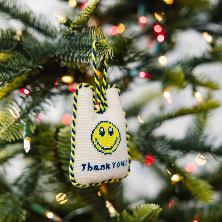 Thank You takeout bag ornament hanging from a Christmas tree branch among string lights