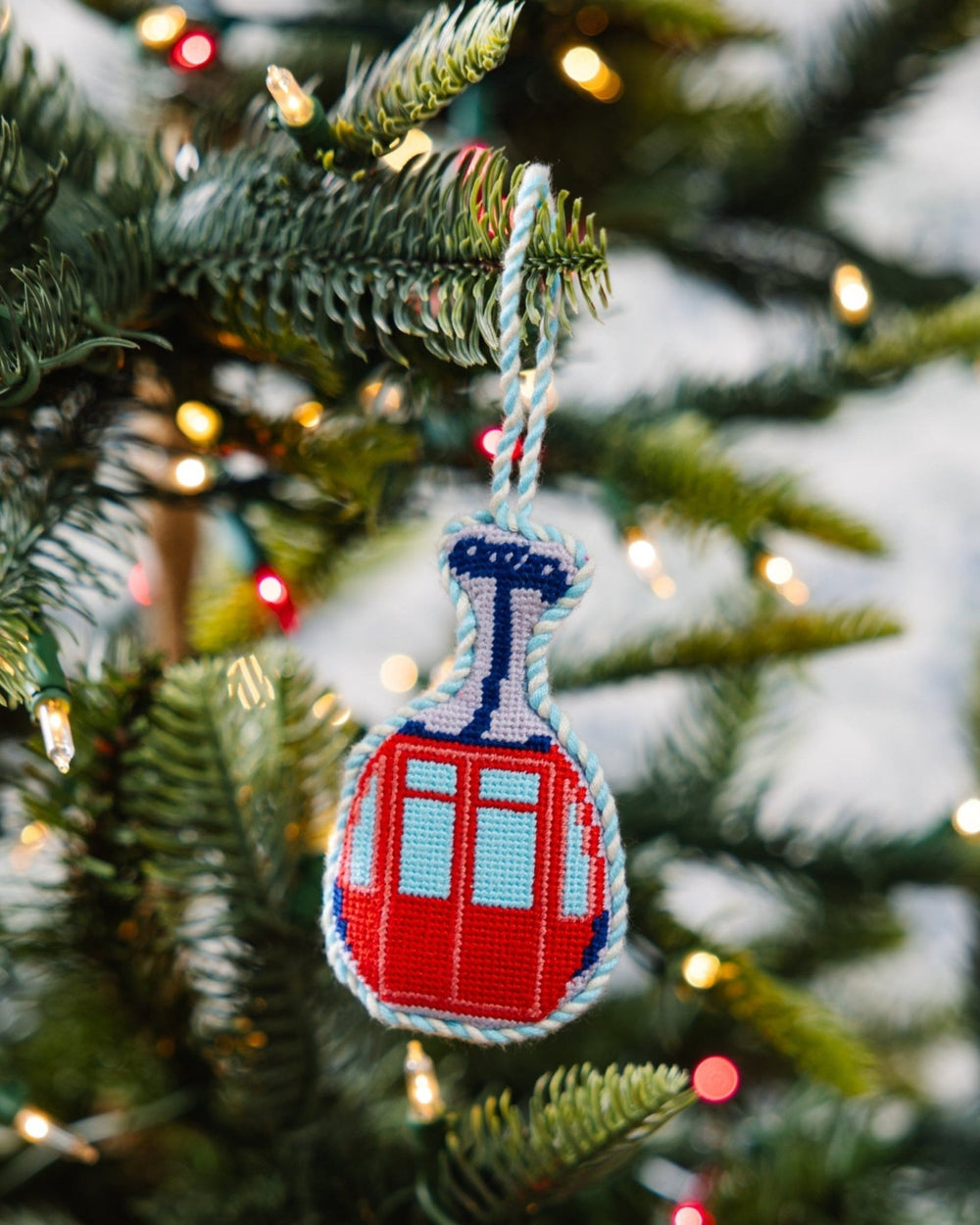 Red gondola ornament hanging on a Christmas tree branch with soft lights
