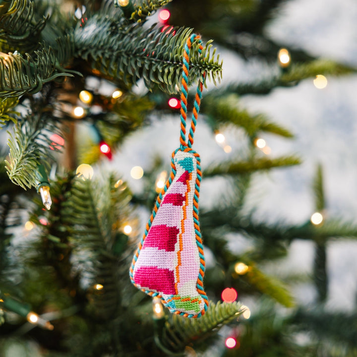 Striped sailboat ornament hanging on a green Christmas tree branch with lights